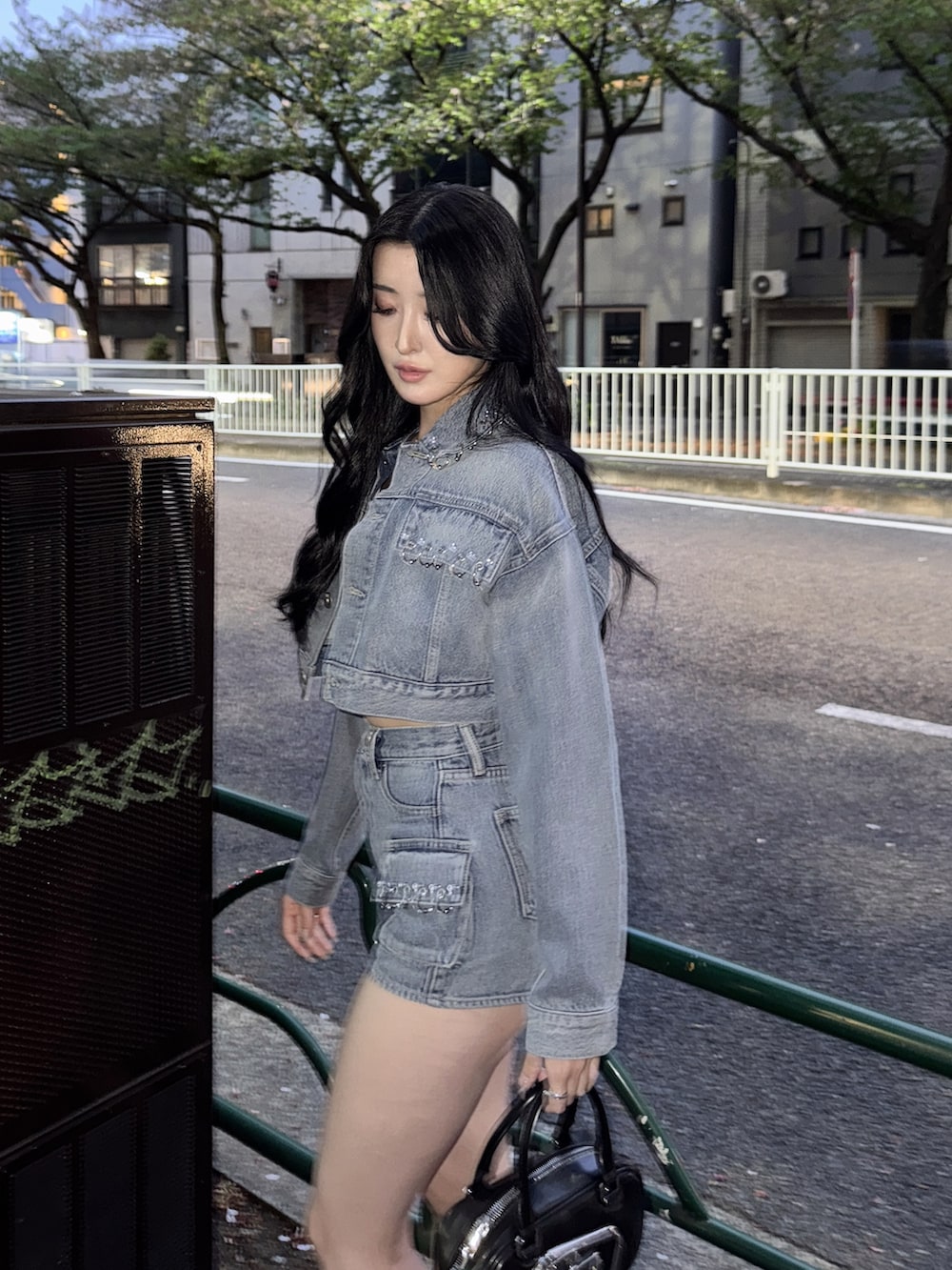 ブルー系のデニムジャケット、ブルー系のデニムパンツ、ブラック系のハンドバッグを着用したレディースの春コーディネートの3枚目の写真