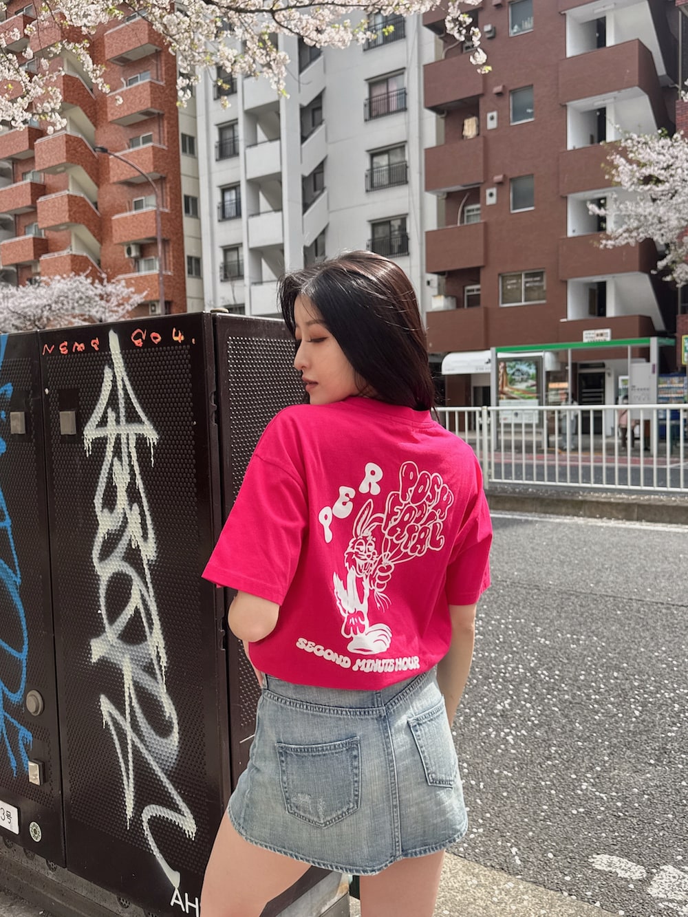 ピンク系のTシャツ/カットソー、ブルー系のデニムスカート、ブラック系のスニーカーを着用したレディースの春コーディネートの2枚目の写真