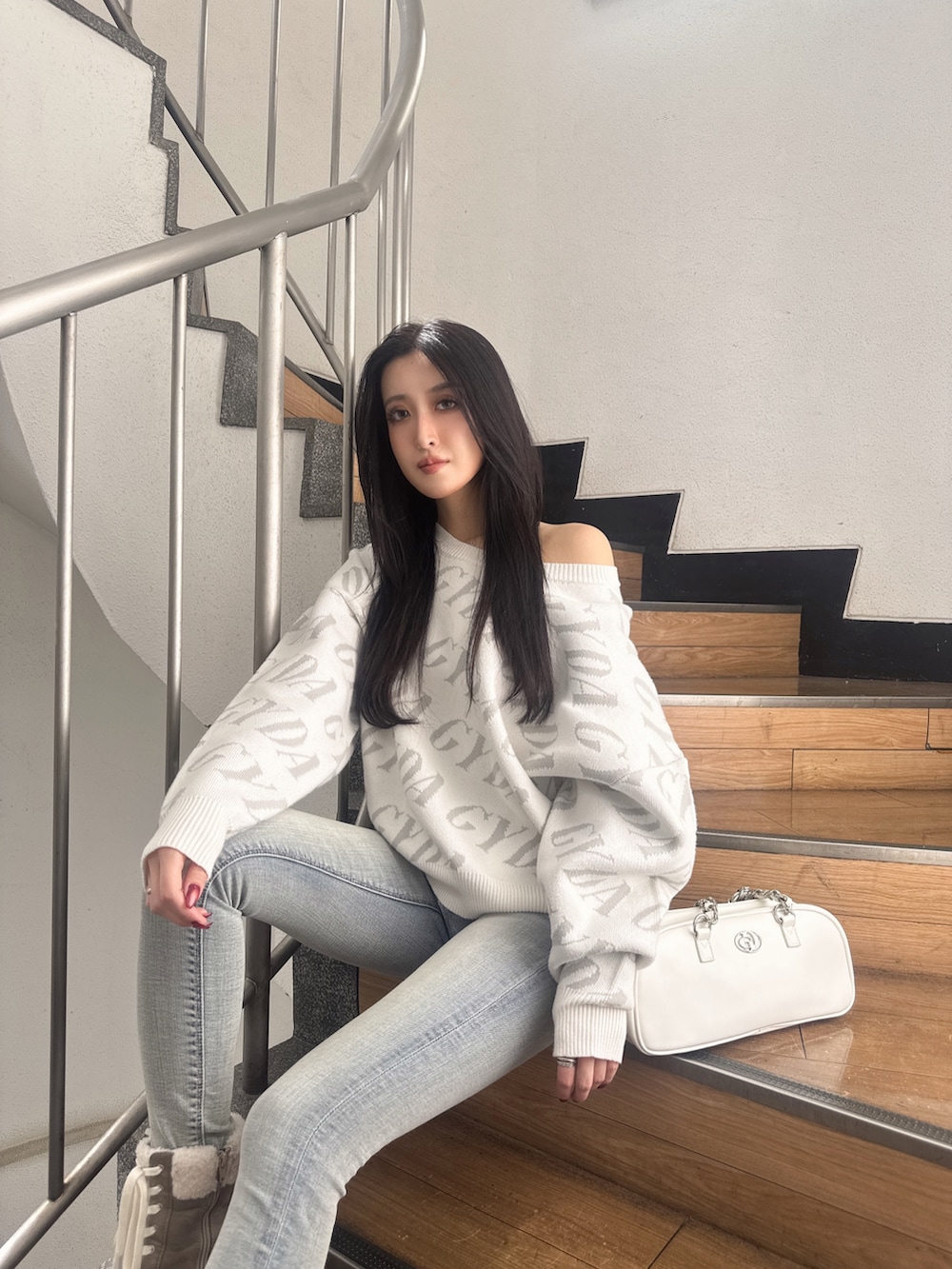 ホワイト系のニット/セーター、ホワイト系のショルダーバッグ、ブルー系のデニムパンツを着用したレディースの秋コーディネートの4枚目の写真