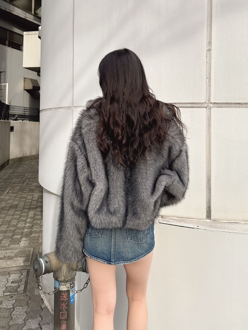 ブラック系のニット/セーター、グレー系のその他アウター、ブルー系のデニムスカートを着用したレディースの冬コーディネートの4枚目の写真