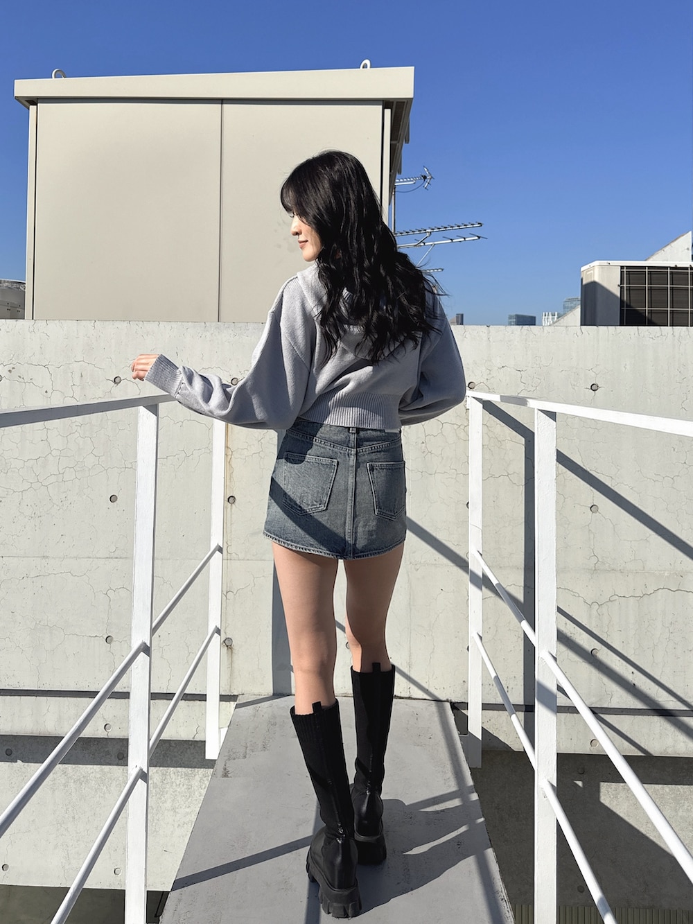 グレー系のニット/セーター、ブルー系のデニムスカート、ブラック系のブーツを着用したレディースの冬コーディネートの3枚目の写真