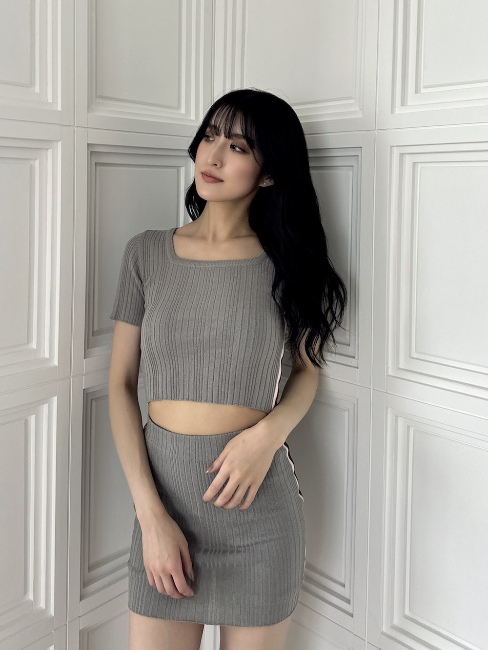 グレー系のニット/セーター、グレー系のスカート、ブラック系のサンダルを着用したレディースの夏コーディネートの4枚目の写真