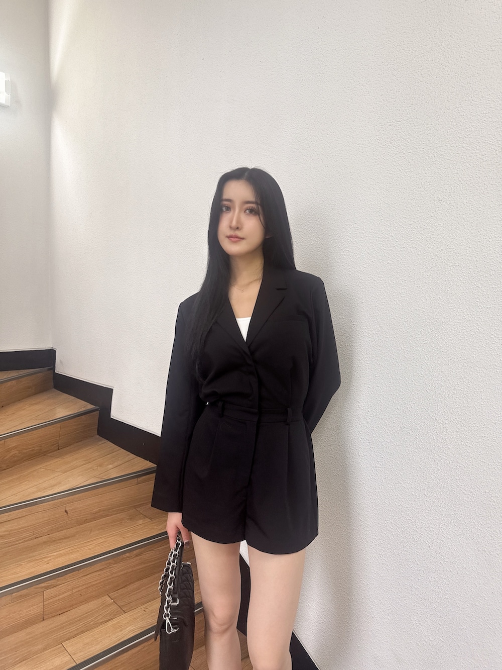 ブラック系のつなぎ/オールインワン、ブラック系のブーツ、ブラック系のハンドバッグを着用したレディースの秋コーディネートの2枚目の写真