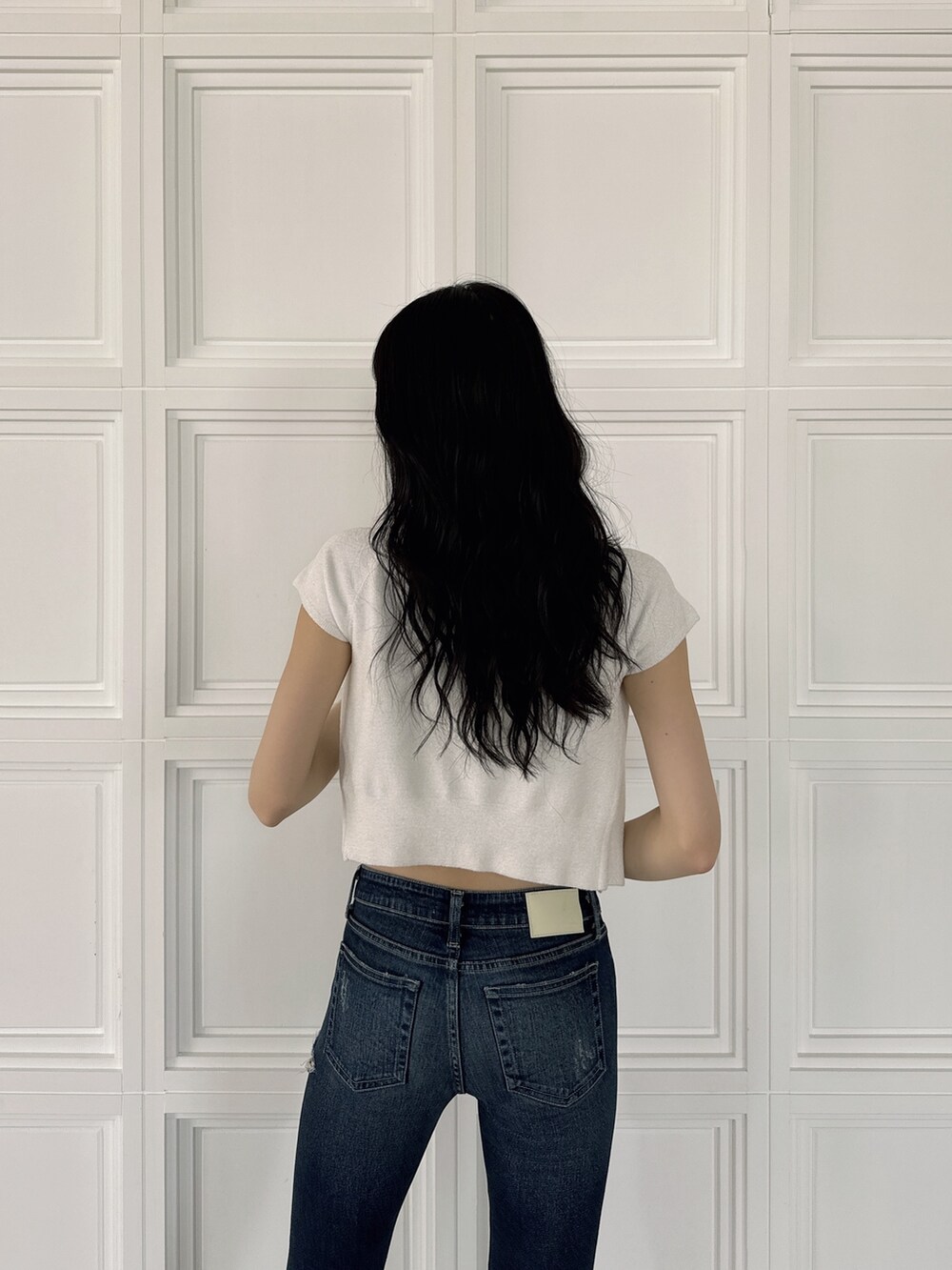 ホワイト系のアンサンブル、ブルー系のデニムパンツ、ホワイト系のサンダルを着用したレディースの夏コーディネートの4枚目の写真