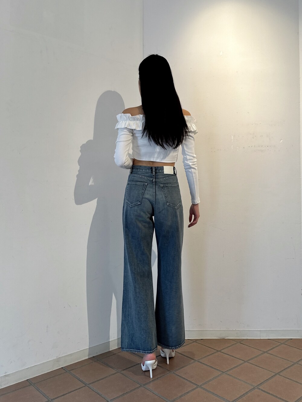 ホワイト系のTシャツ/カットソー、ブルー系のデニムパンツ、ホワイト系のパンプスを着用したレディースの冬コーディネートの2枚目の写真