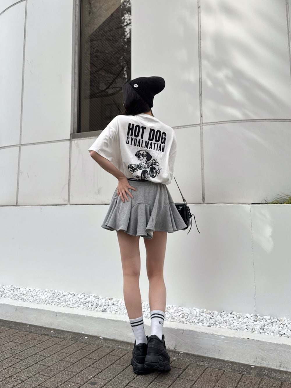 ホワイト系のTシャツ/カットソー、グレー系のスカート、ブラック系のスニーカーを着用したレディースの春コーディネートの4枚目の写真