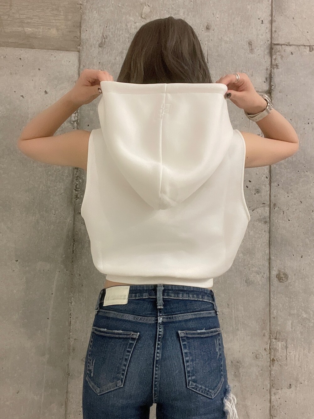 ホワイト系のパーカー、ブラック系のサンダル、ブルー系のデニムパンツを着用したレディースの夏コーディネートの4枚目の写真