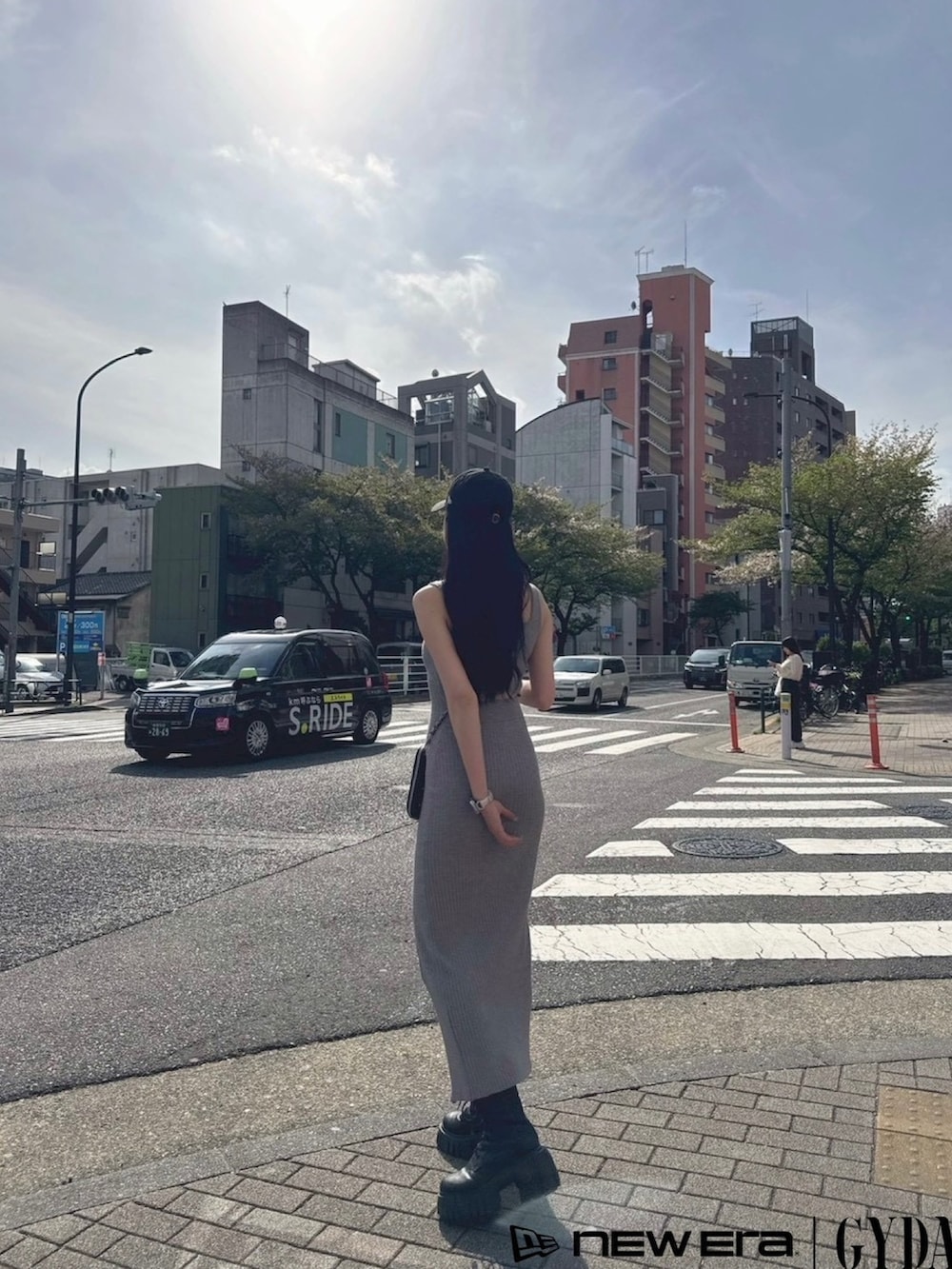 グレー系のワンピース、ブラック系のショルダーバッグ、ブラック系のキャップを着用したレディースの春コーディネートの3枚目の写真
