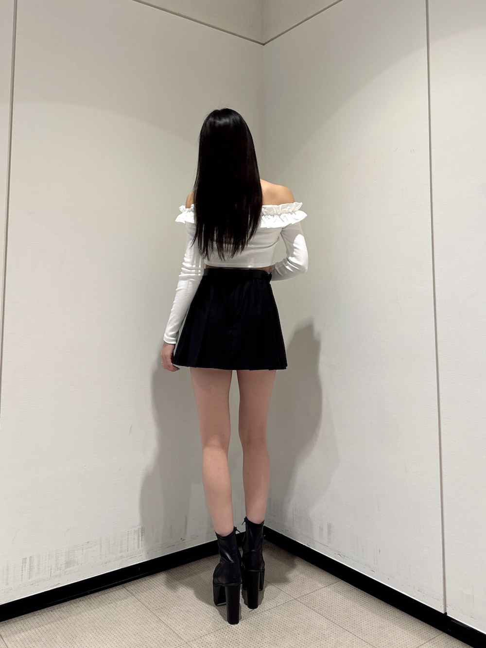 ホワイト系のTシャツ/カットソー、ブラック系のスカート、ブラック系のブーツを着用したレディースの冬コーディネートの2枚目の写真