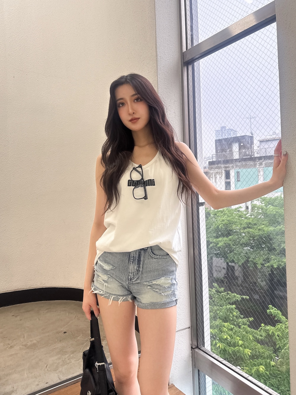 ホワイト系のワンピース、ブルー系のデニムパンツ、ブラック系のハンドバッグを着用したレディースの夏コーディネートの4枚目の写真