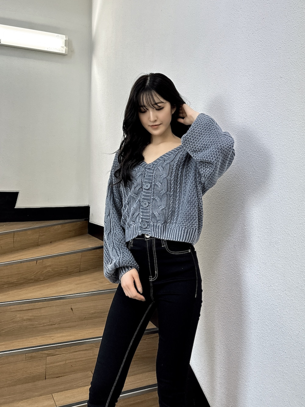 ブルー系のニット/セーター、ブラック系のデニムパンツ、ブラック系のブーツを着用したレディースの夏コーディネートの2枚目の写真