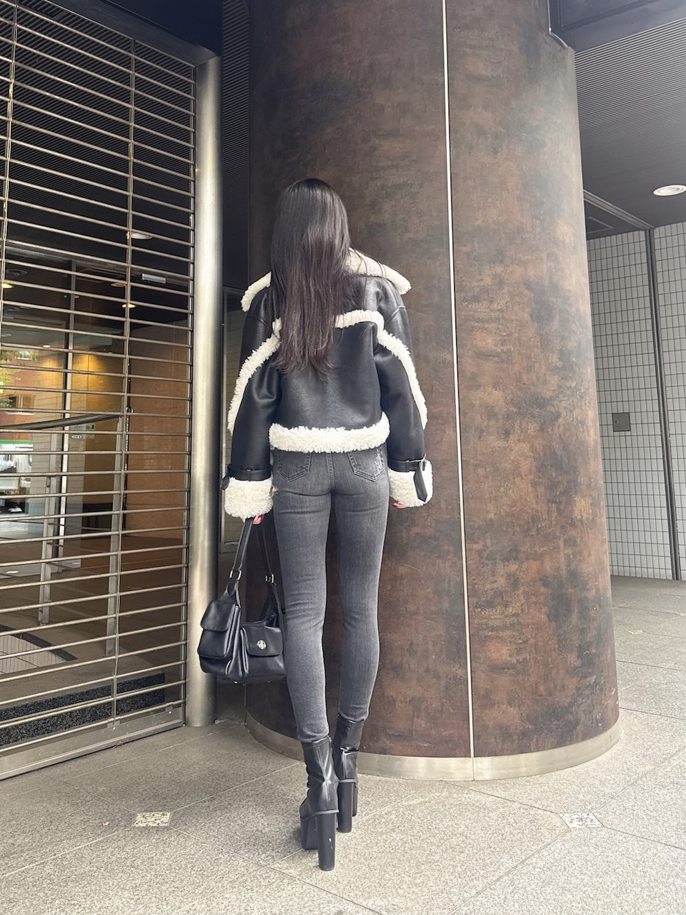 ブラック系のムートンコート、ブラック系のTシャツ/カットソー、ブラック系のデニムパンツを着用したレディースの秋コーディネートの3枚目の写真