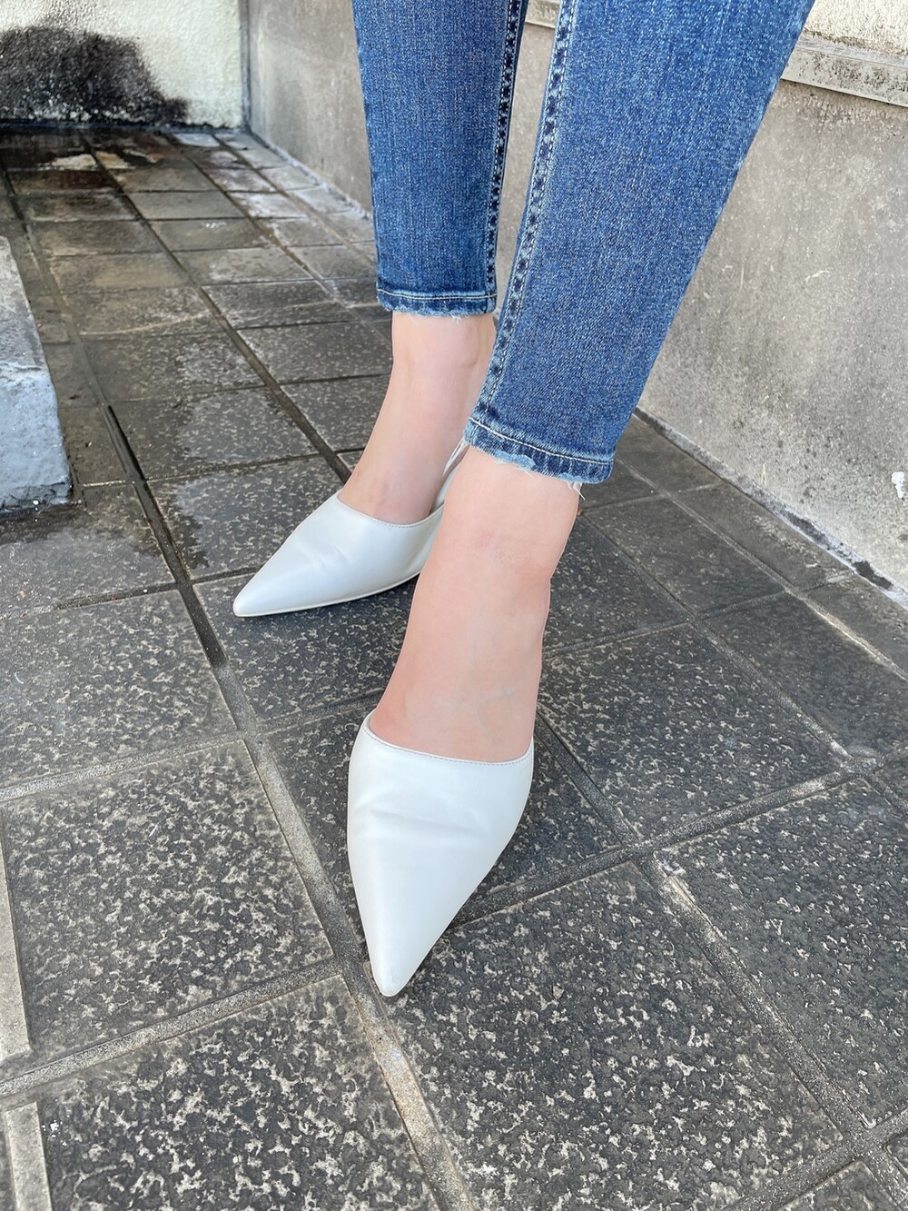ブルー系のデニムパンツ、グレー系のニット/セーター、ホワイト系のパンプスを着用したレディースの冬コーディネートの5枚目の写真