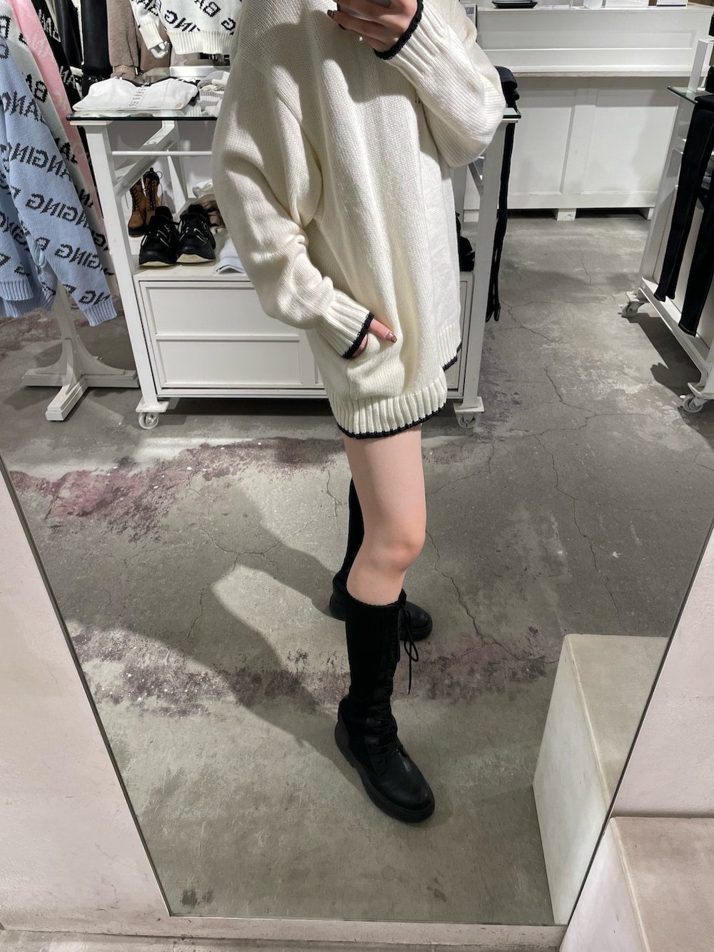 ホワイト系のニット/セーター、ブラック系のスカート、ブラック系のブーツを着用したレディースの冬コーディネートの4枚目の写真