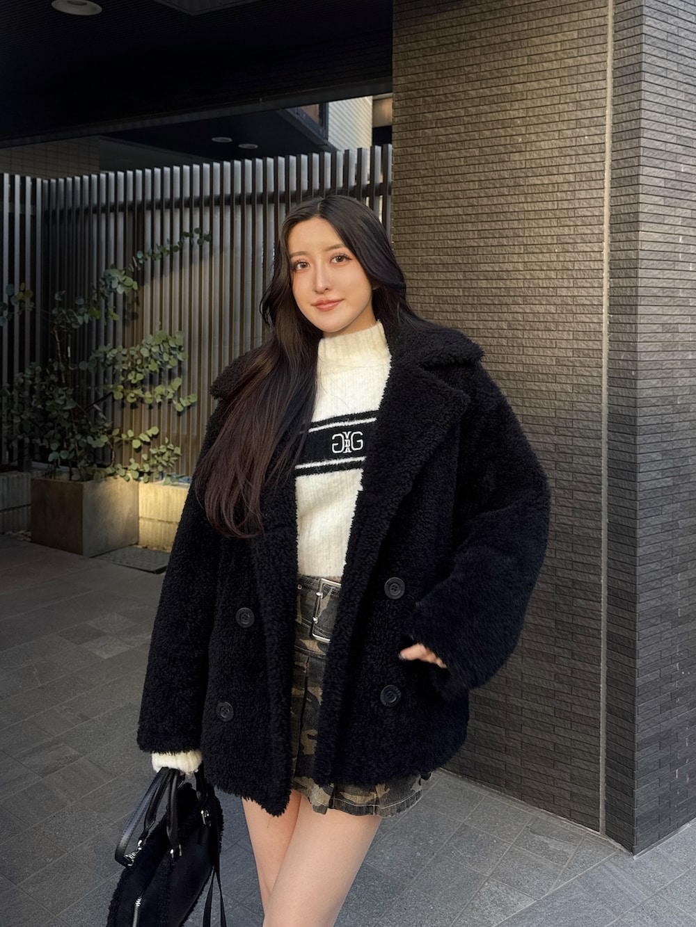 ホワイト系のニット/セーター、ブラック系のブルゾン、その他のデニムスカートを着用したレディースの冬コーディネートの2枚目の写真