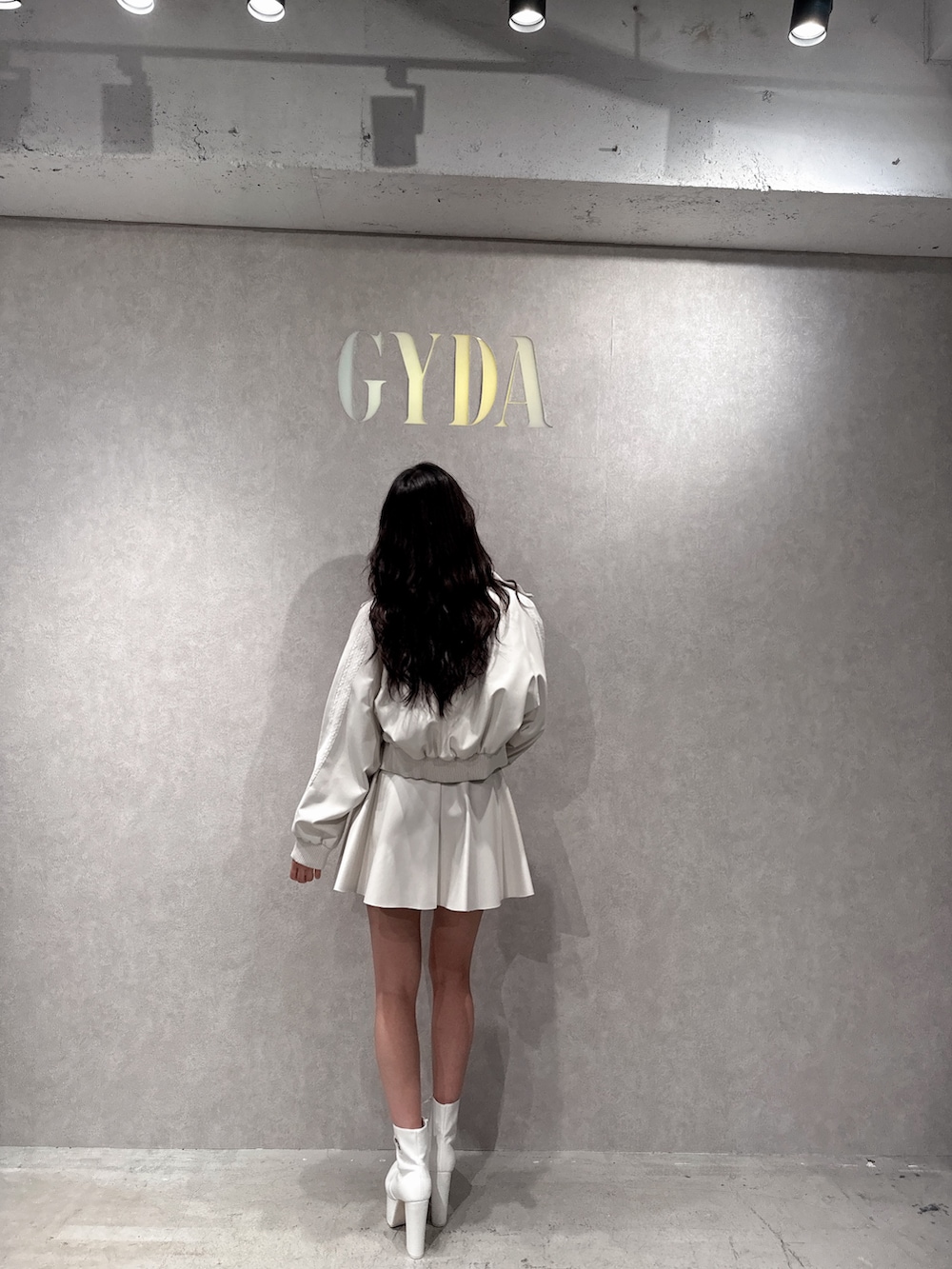 ホワイト系のブルゾン、ホワイト系のニット/セーター、ホワイト系のスカートを着用したレディースの冬コーディネートの2枚目の写真