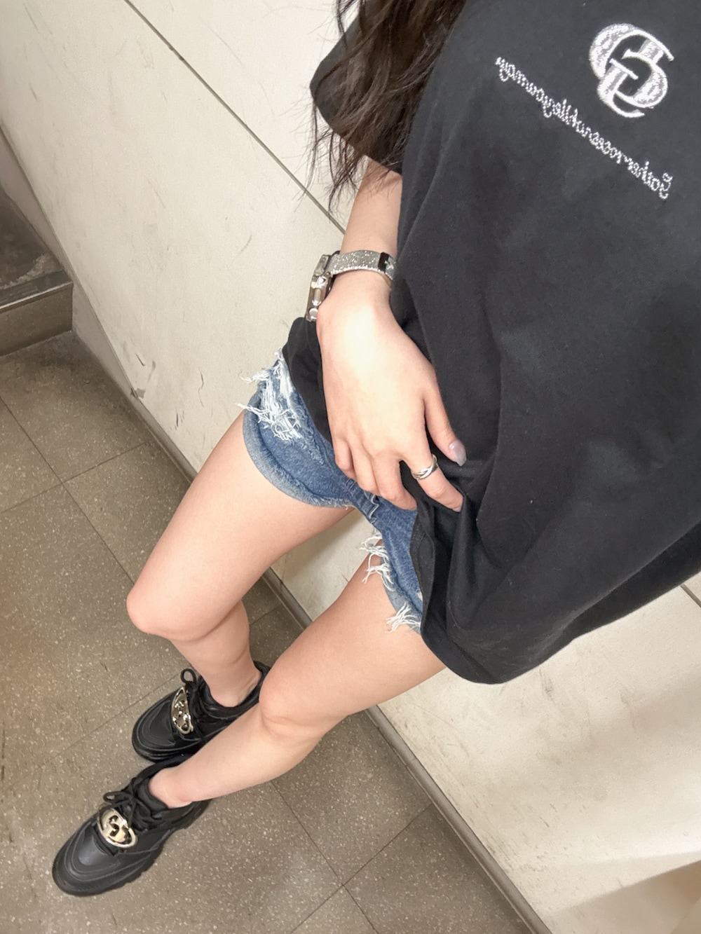 ブラック系のTシャツ/カットソー、ブラック系のスニーカー、ブルー系のデニムパンツを着用したレディースの春コーディネートの2枚目の写真