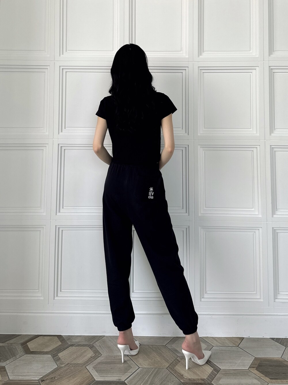 ブラック系のスウェットパンツ、ブラック系のTシャツ/カットソー、ホワイト系のパンプスを着用したレディースの夏コーディネートの2枚目の写真