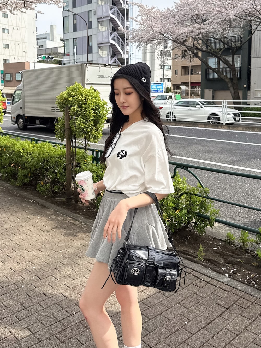 ホワイト系のTシャツ/カットソー、グレー系のスカート、ブラック系のスニーカーを着用したレディースの春コーディネートの3枚目の写真