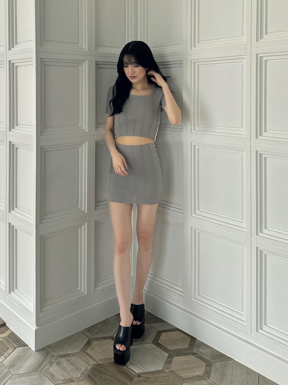 グレー系のニット/セーター、グレー系のスカート、ブラック系のサンダルを着用したレディースの夏コーディネートの2枚目の写真