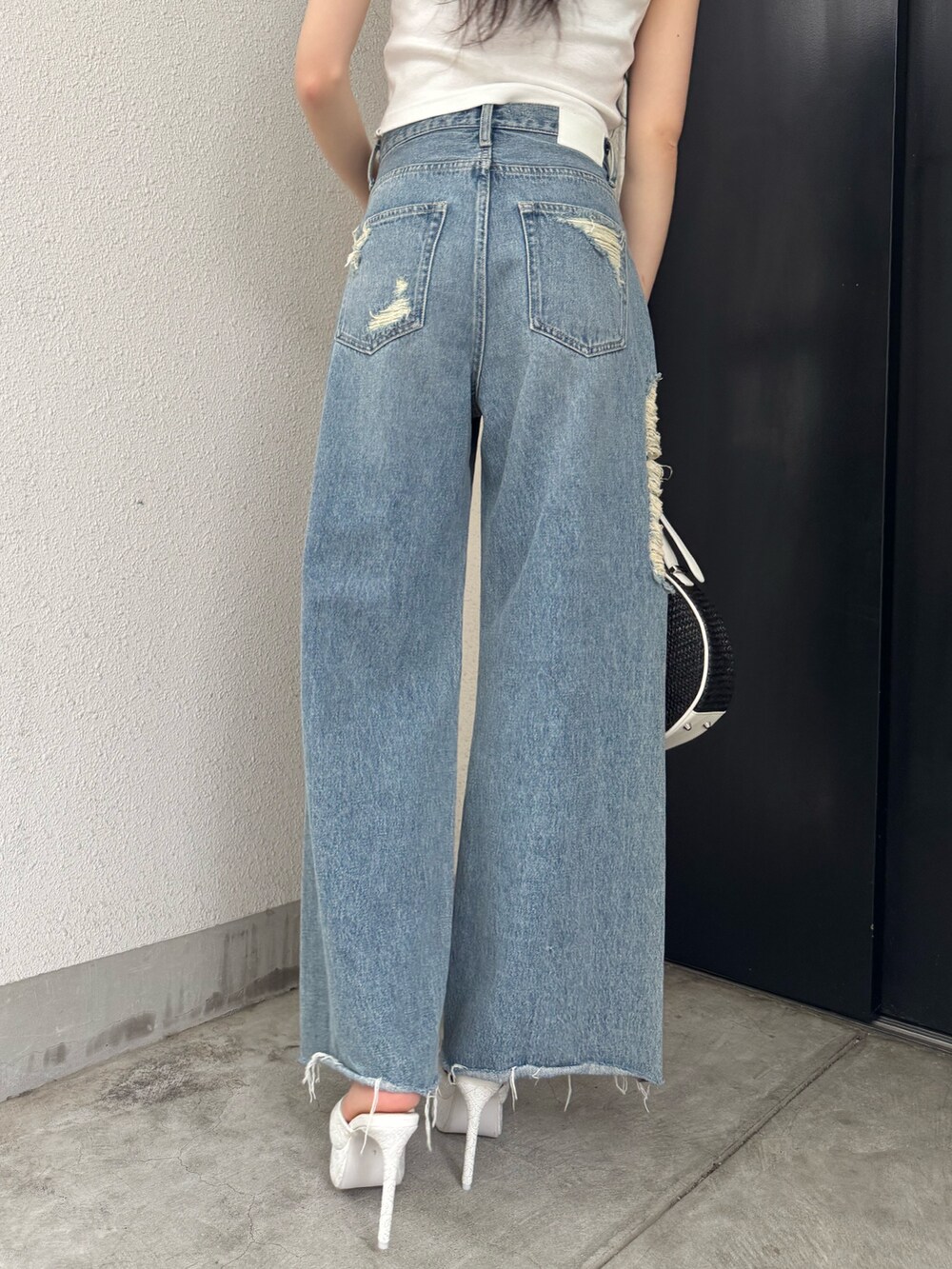 ホワイト系のタンクトップ、ブルー系のデニムパンツ、ホワイト系のパンプスを着用したレディースの夏コーディネートの5枚目の写真