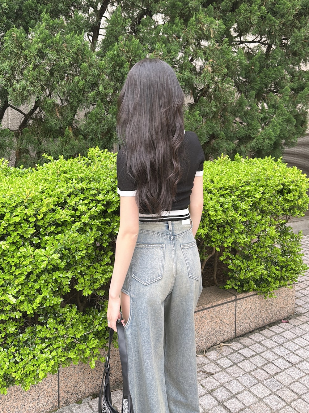 ブラック系のニット/セーター、ブルー系のデニムパンツ、ブラック系のパンプスを着用したレディースの春コーディネートの4枚目の写真