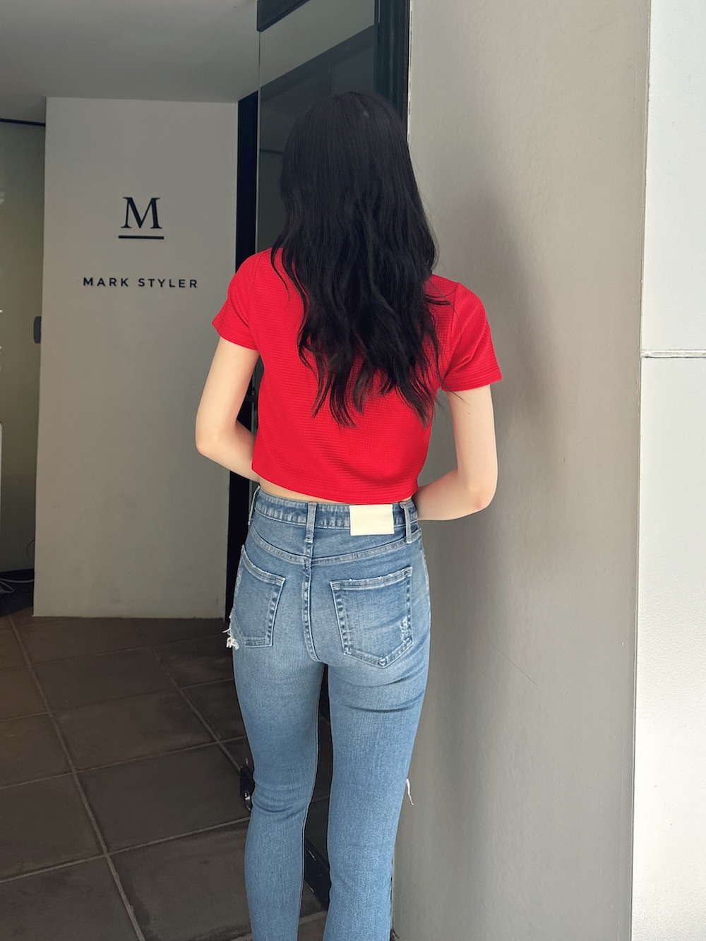 レッド系のTシャツ/カットソー、ブルー系のデニムパンツ、ブラック系のサンダルを着用したレディースの夏コーディネートの3枚目の写真