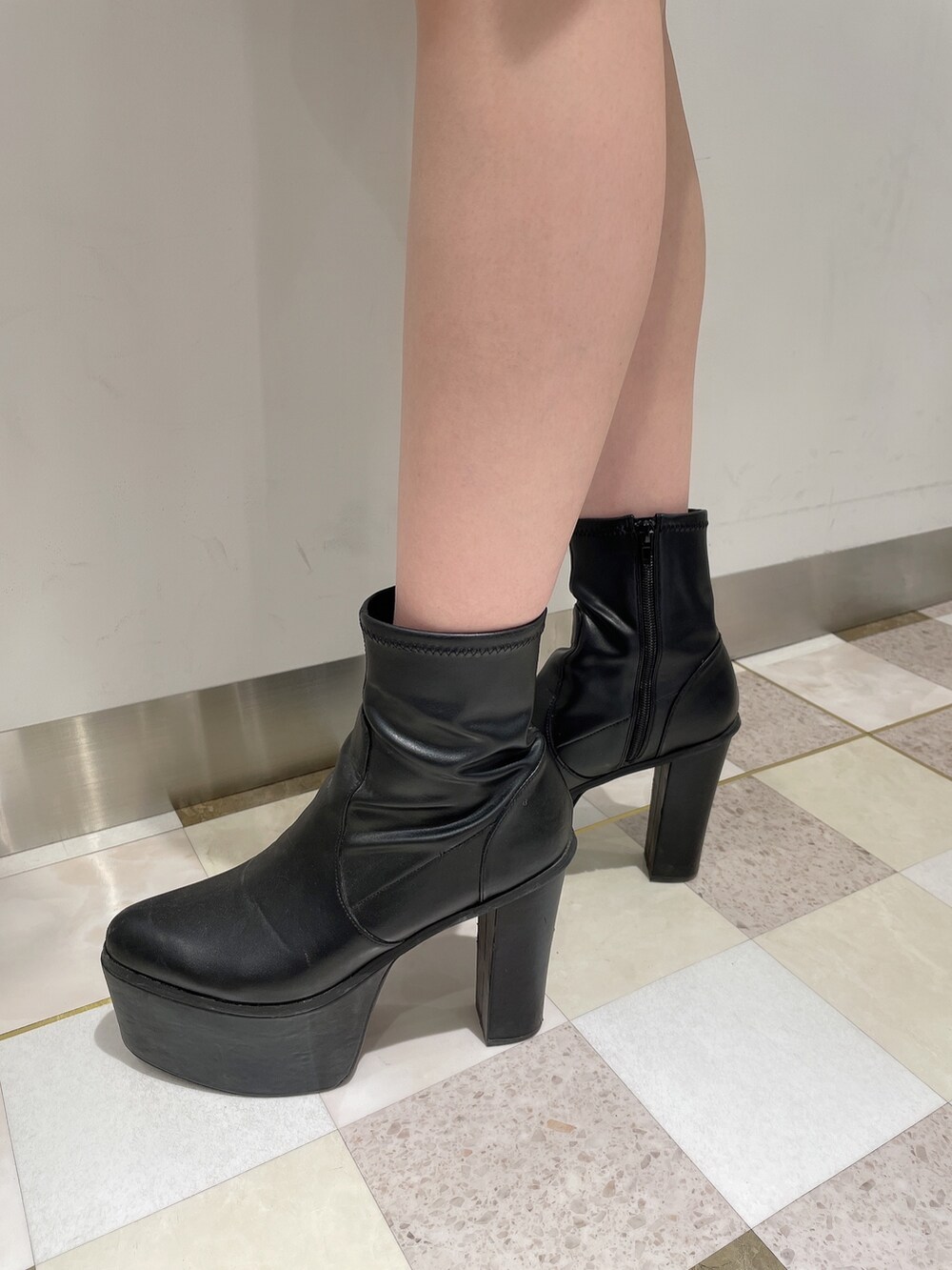 グレー系のワンピース、ブラック系のデニムパンツ、ブラック系のブーツを着用したレディースの冬コーディネートの7枚目の写真