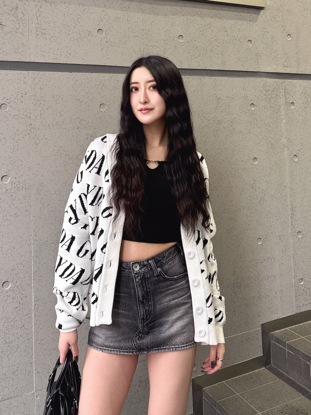 ホワイト系のカーディガン/ボレロ、ブラック系のTシャツ/カットソー、ブラック系のデニムスカートを着用したレディースの春コーディネートの2枚目の写真