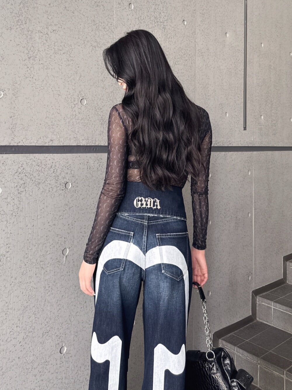 ブラック系のTシャツ/カットソー、ブルー系のデニムパンツ、ブラック系のパンプスを着用したレディースの夏コーディネートの6枚目の写真