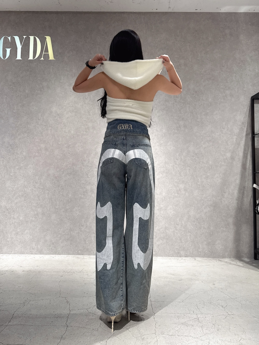 ホワイト系のニット/セーター、ブルー系のデニムパンツ、ホワイト系のパンプスを着用したレディースの秋コーディネートの3枚目の写真