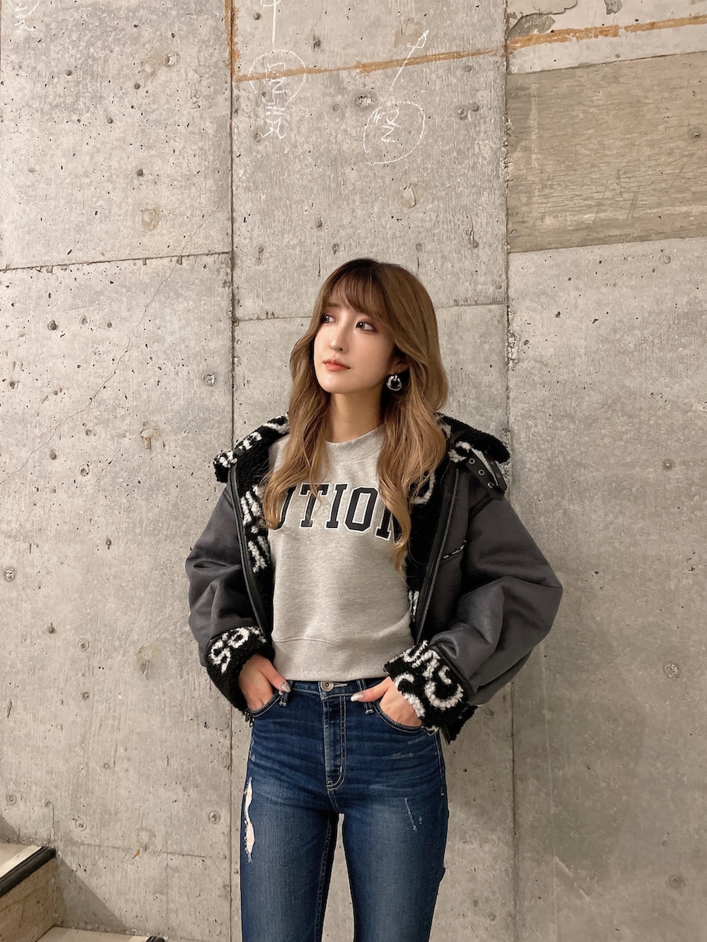 ブラック系のブルゾン、グレー系のスウェット、ブルー系のデニムパンツを着用したレディースの秋コーディネートの4枚目の写真