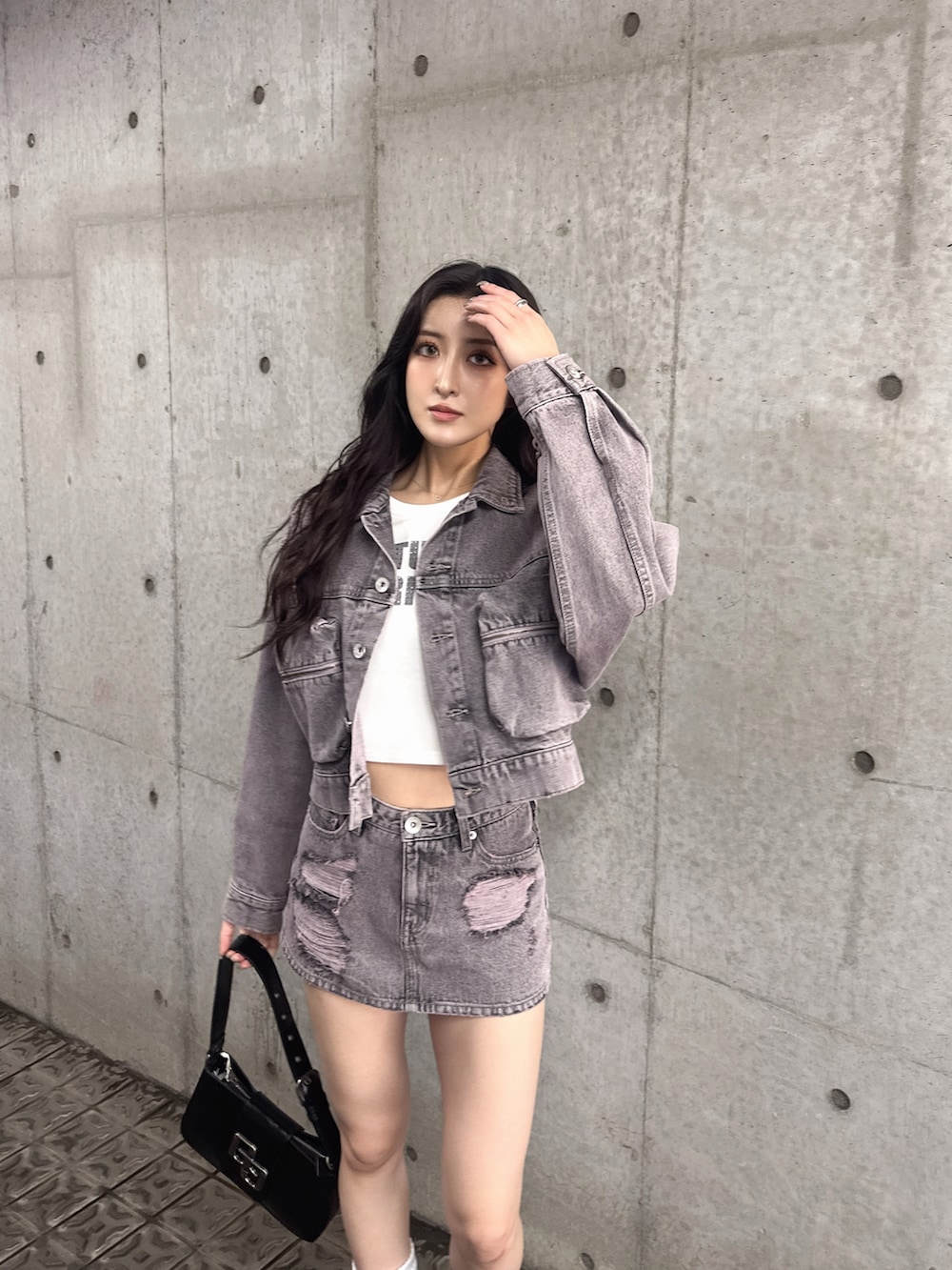 ブラック系のハンドバッグ、ブラック系のブーツ、ピンク系のデニムスカートを着用したレディースの夏コーディネートの3枚目の写真