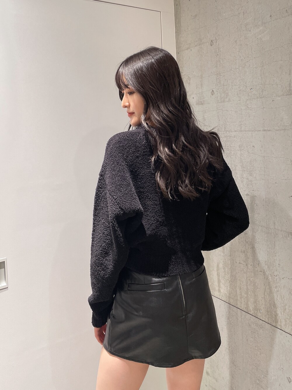 ブラック系のニット/セーター、ブラック系のスカート、ブラック系のブーツを着用したレディースの秋コーディネートの4枚目の写真