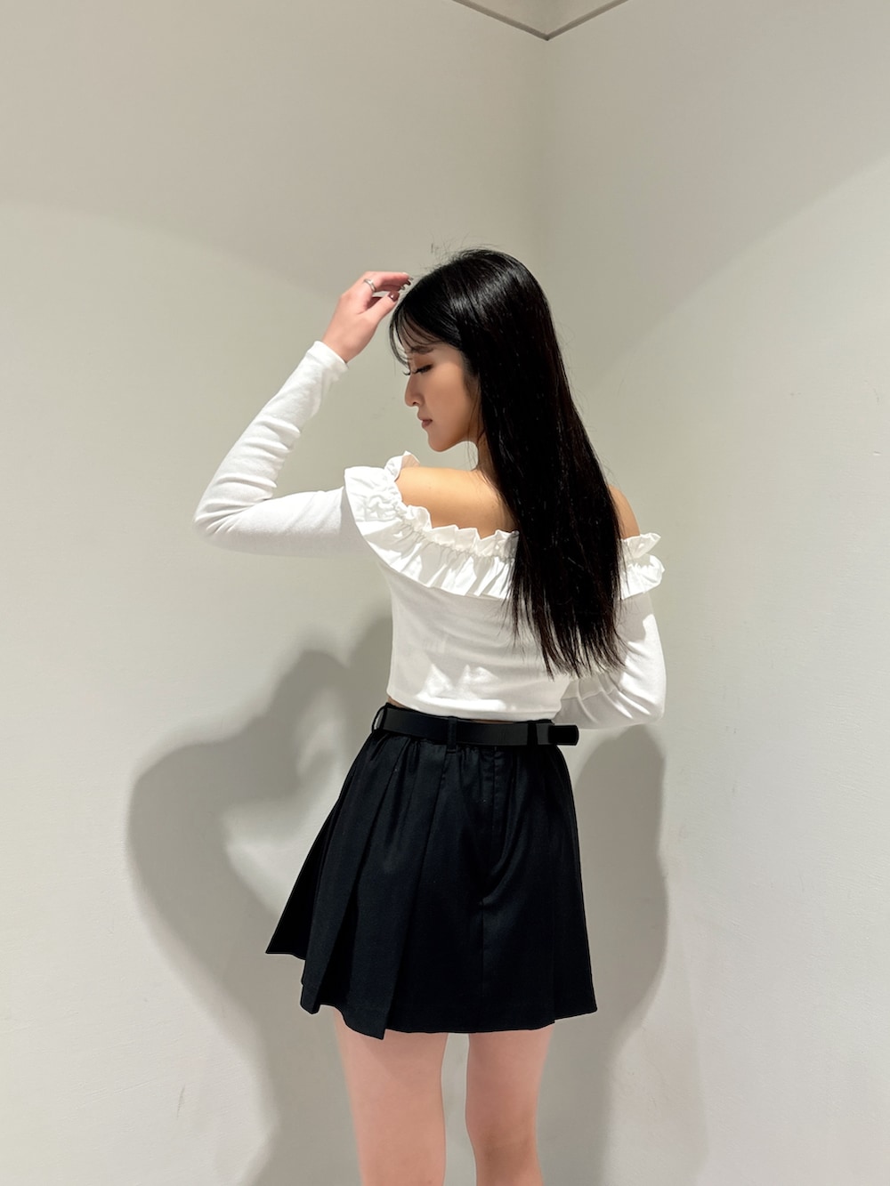 ホワイト系のTシャツ/カットソー、ブラック系のスカート、ブラック系のブーツを着用したレディースの冬コーディネートの4枚目の写真