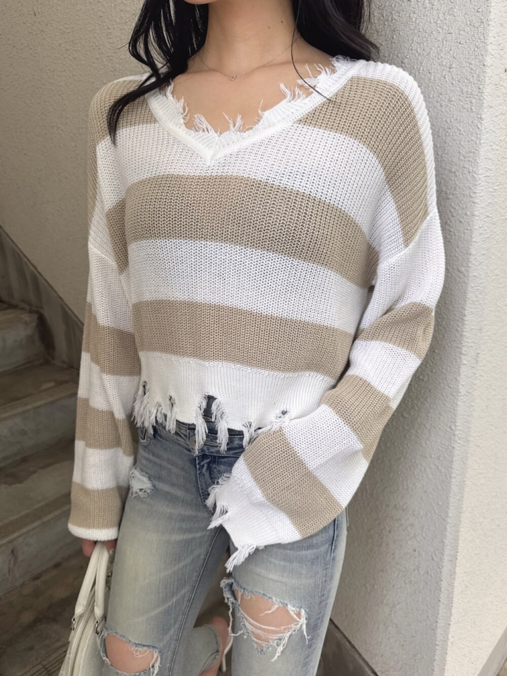ベージュ系のニット/セーター、ブルー系のデニムパンツ、ホワイト系のハンドバッグを着用したレディースの夏コーディネートの6枚目の写真