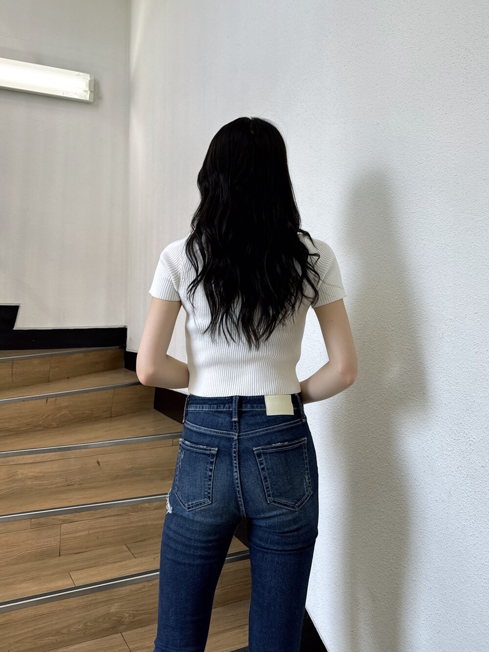 ホワイト系のニット/セーター、ブルー系のデニムパンツ、ホワイト系のサンダルを着用したレディースの夏コーディネートの4枚目の写真