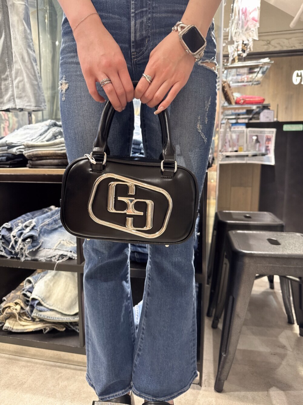 ブラック系のハンドバッグ、ブルー系のデニムパンツ、ブラック系のサンダルを着用したレディースの夏コーディネートの7枚目の写真