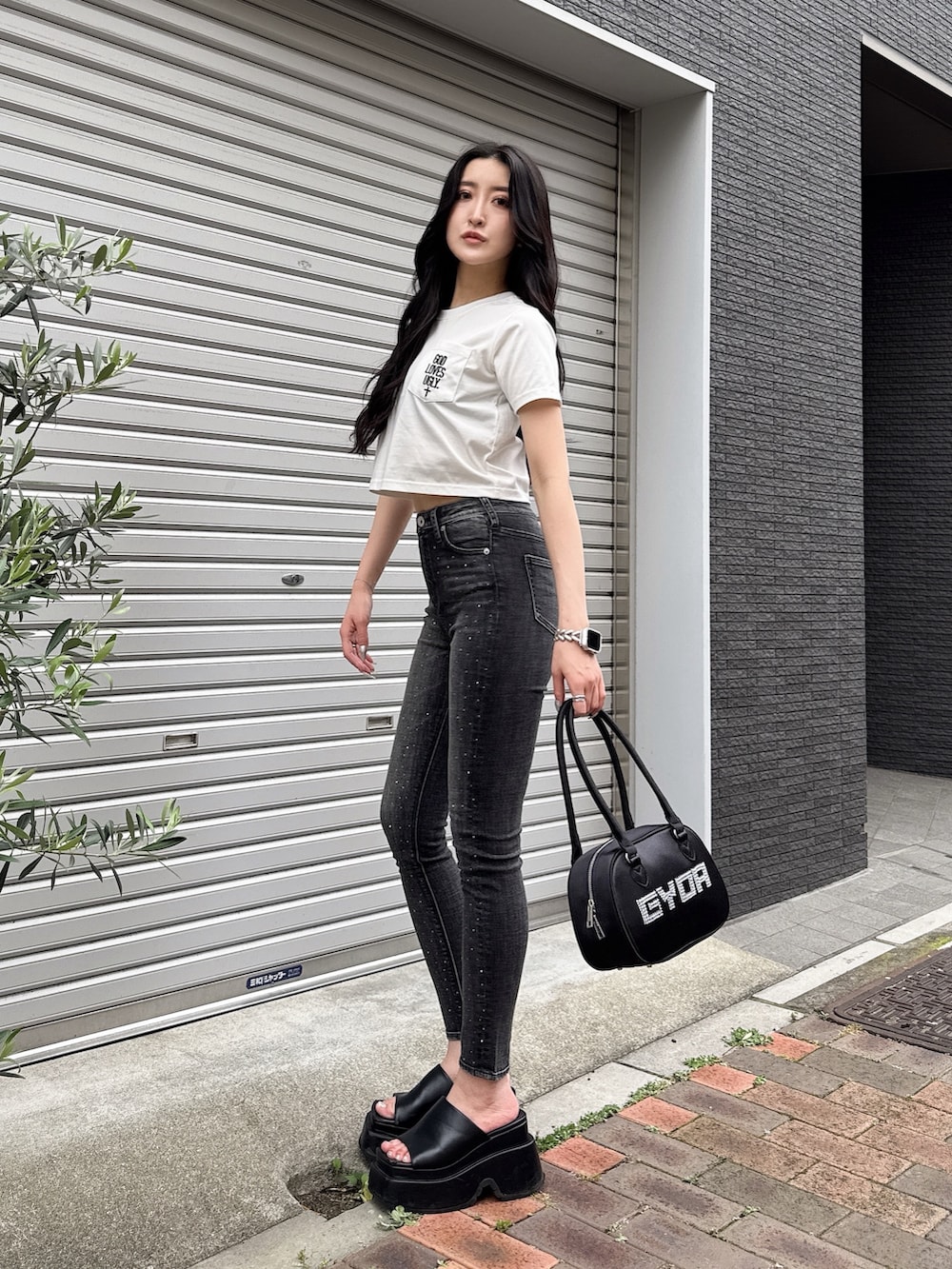 ホワイト系のTシャツ/カットソー、ブラック系のデニムパンツ、ブラック系のボストンバッグを着用したレディースの夏コーディネートの2枚目の写真