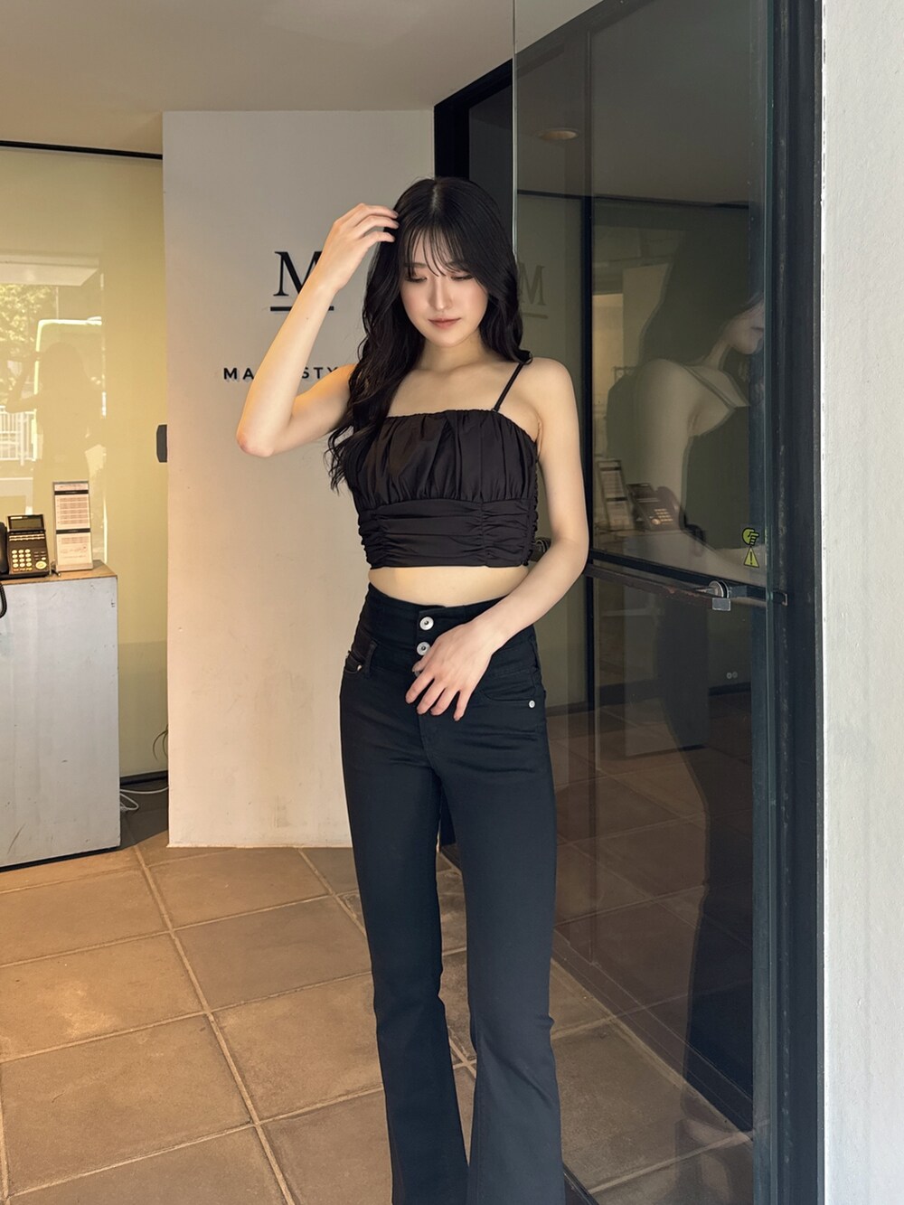 ブラック系のキャミソール、ブラック系のデニムパンツ、ブラック系のサンダルを着用したレディースの夏コーディネートの3枚目の写真