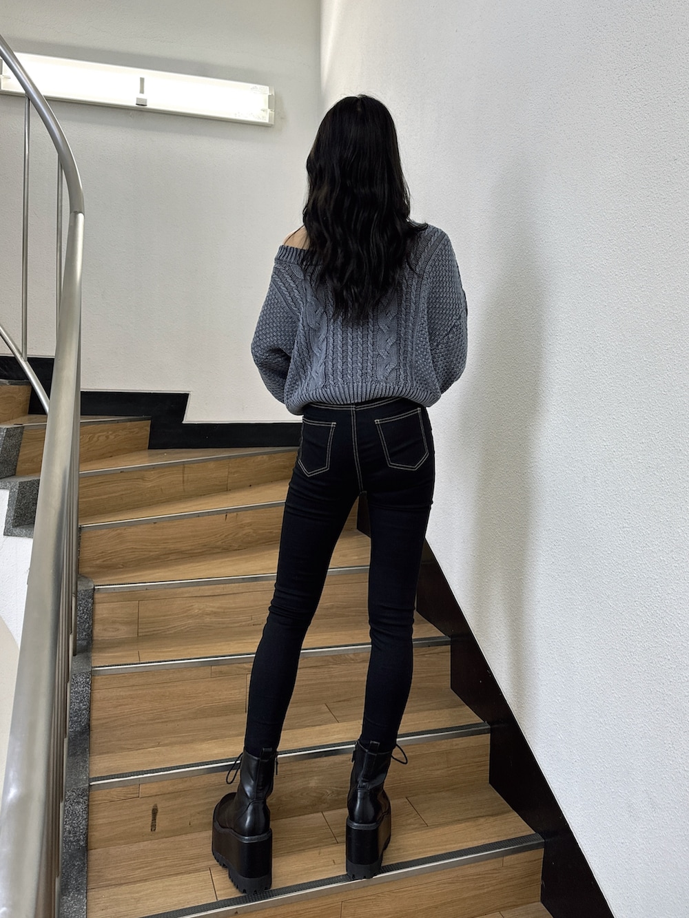 ブルー系のニット/セーター、ブラック系のデニムパンツ、ブラック系のブーツを着用したレディースの夏コーディネートの3枚目の写真