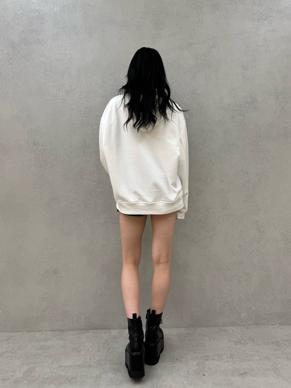 ホワイト系のパーカー、ブラック系のその他パンツ、ブラック系のブーツを着用したレディースの秋コーディネートの2枚目の写真