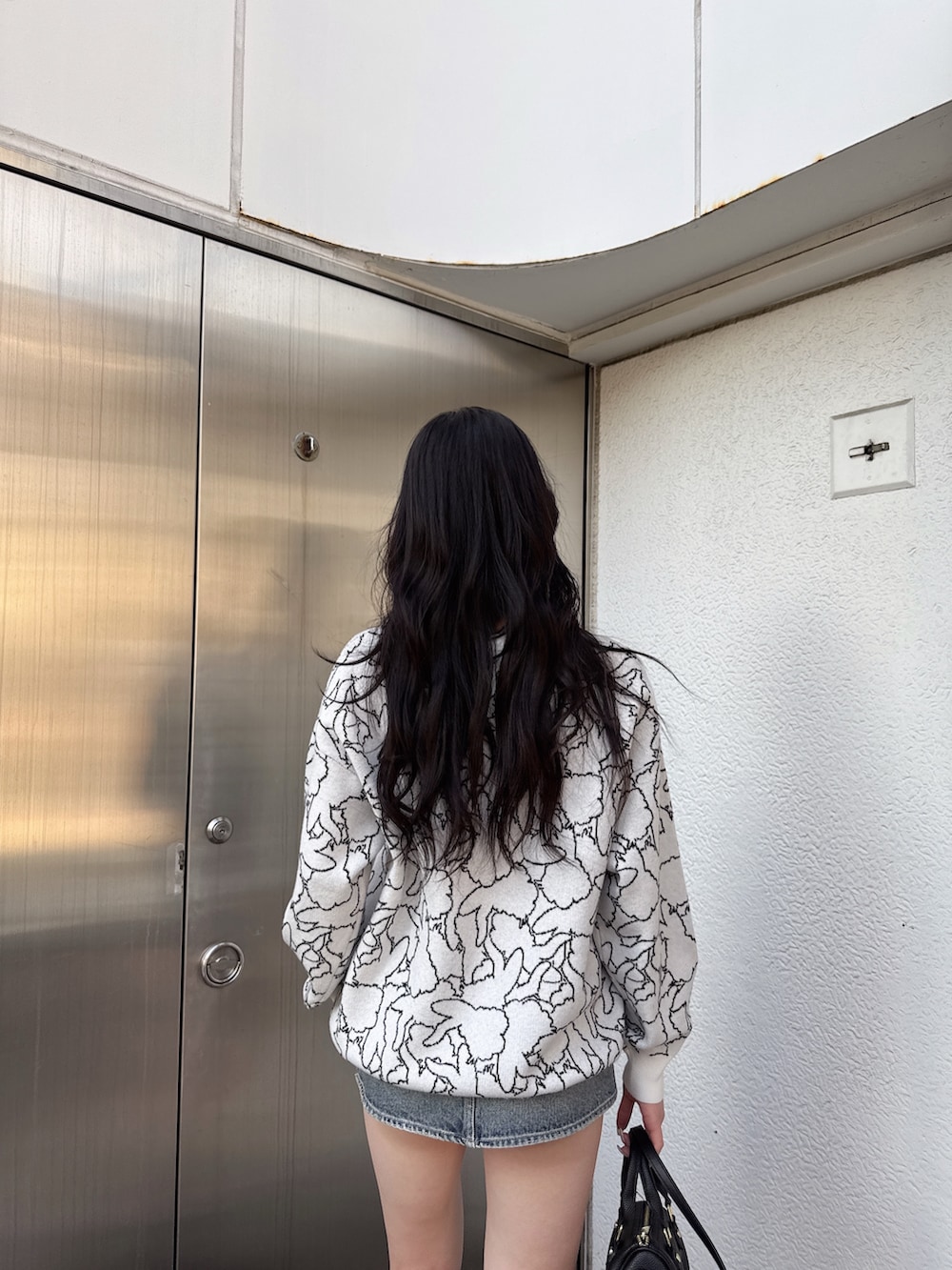 ホワイト系のニット/セーター、ブルー系のデニムスカート、ブラック系のブーツを着用したレディースの冬コーディネートの3枚目の写真