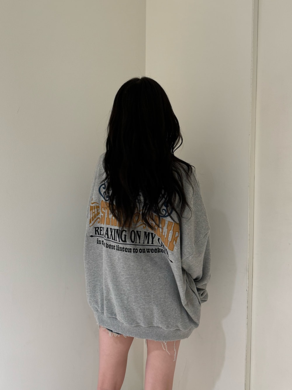 グレー系のスウェット、ブルー系のデニムパンツ、ベージュ系のスリッポンを着用したレディースの夏コーディネートの2枚目の写真