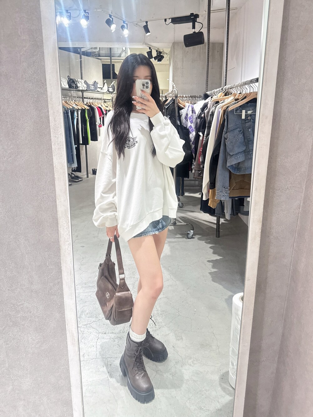 ホワイト系のスウェット、ブルー系のデニムスカート、ブラウン系のブーツを着用したレディースの夏コーディネートの3枚目の写真