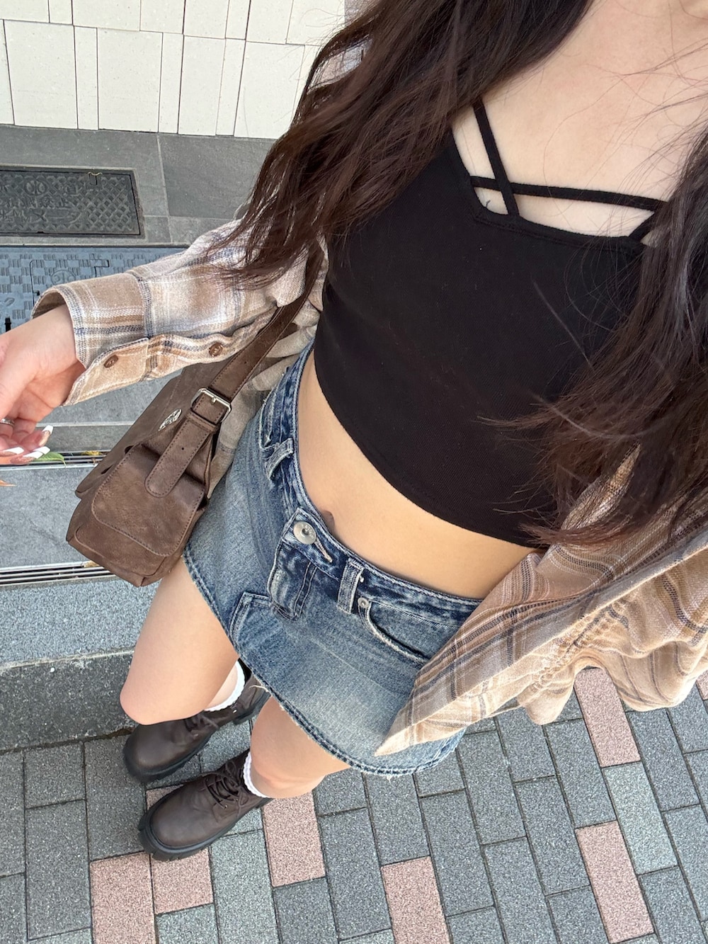 ブルー系のデニムスカート、ブラウン系のハンドバッグ、ベージュ系のシャツ/ブラウスを着用したレディースの夏コーディネートの6枚目の写真