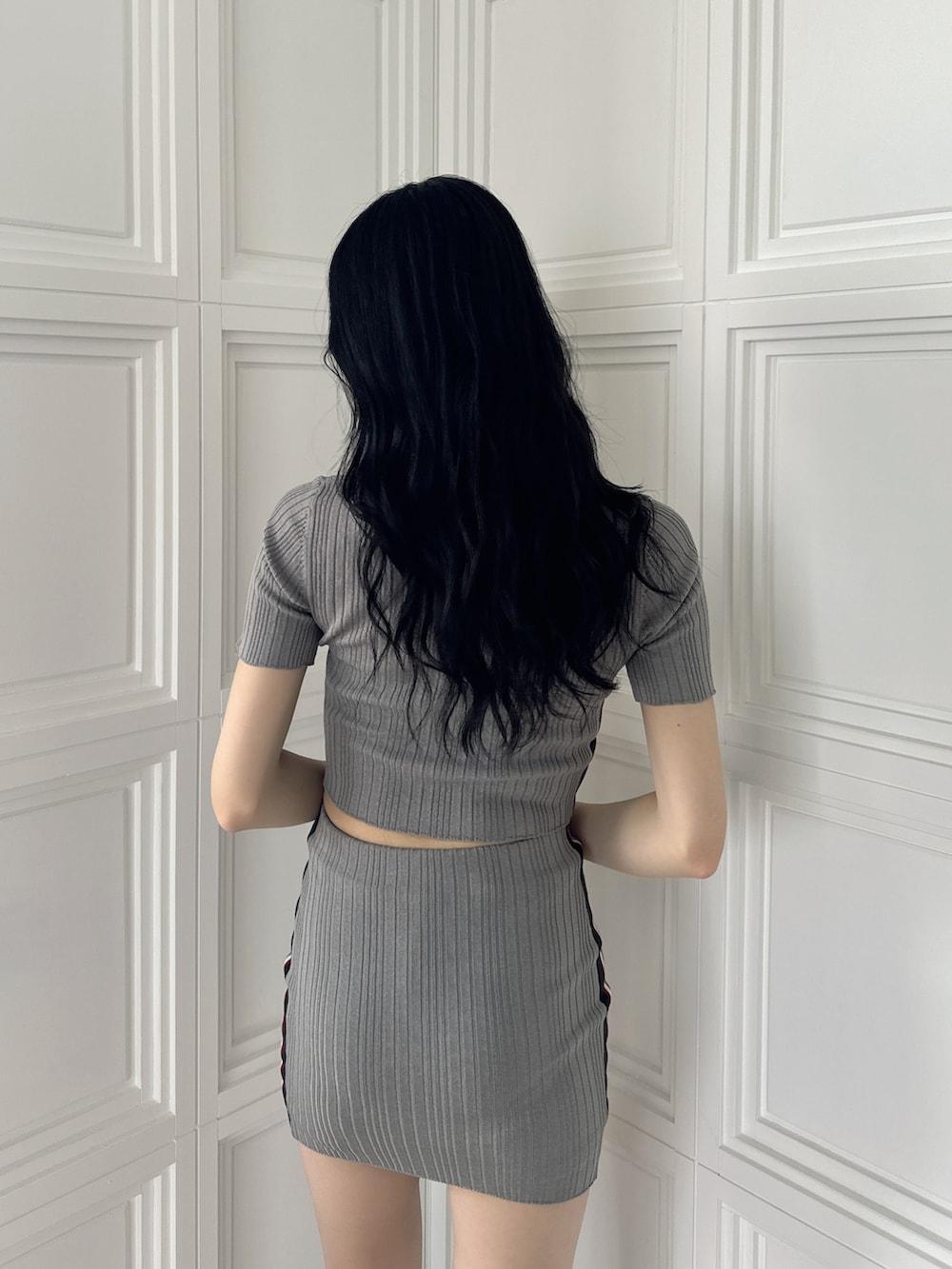 グレー系のニット/セーター、グレー系のスカート、ブラック系のサンダルを着用したレディースの夏コーディネートの6枚目の写真