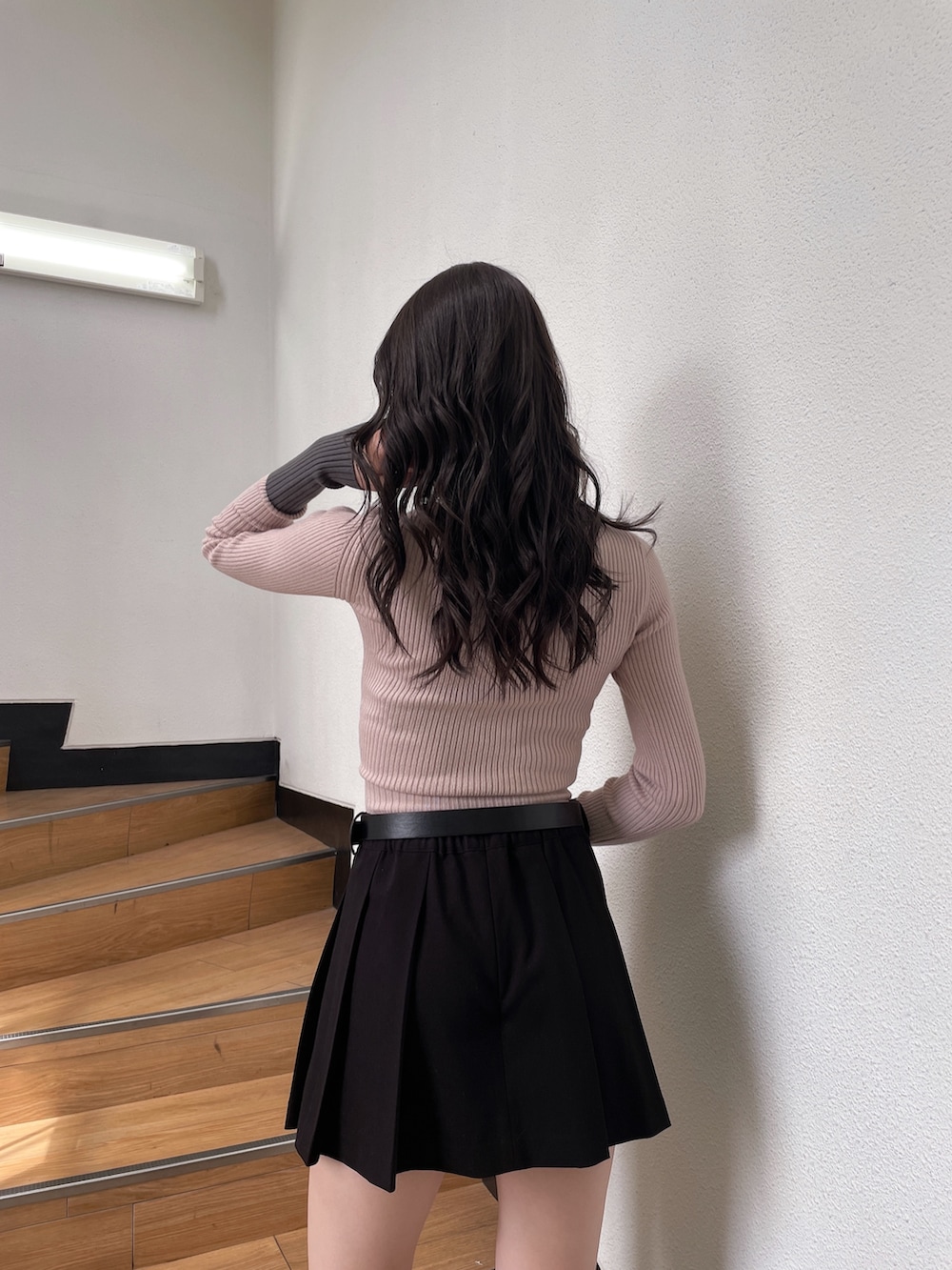 ピンク系のニット/セーター、ブラック系のスカート、ブラック系のブーツを着用したレディースの秋コーディネートの4枚目の写真