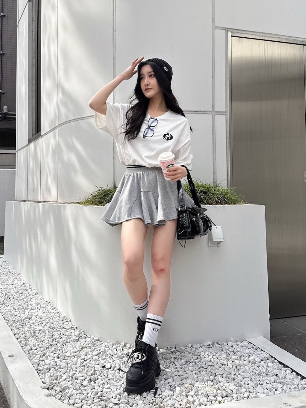 ホワイト系のTシャツ/カットソー、グレー系のスカート、ブラック系のスニーカーを着用したレディースの春コーディネートの2枚目の写真