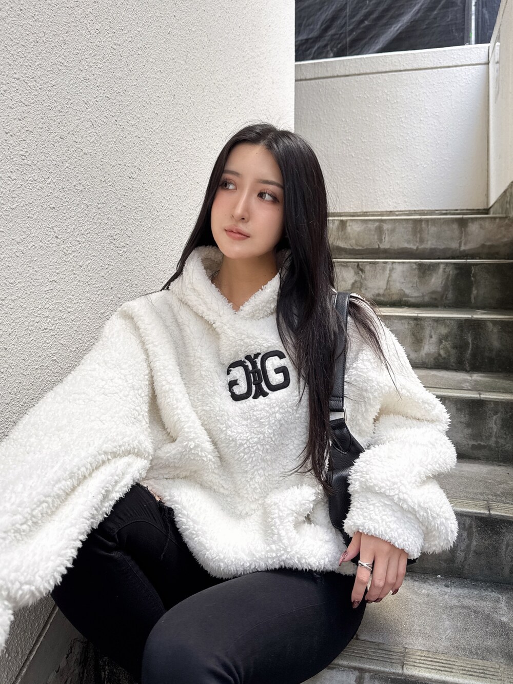 ホワイト系のパーカー、ブラック系のデニムパンツを着用したレディースの秋コーディネートの2枚目の写真